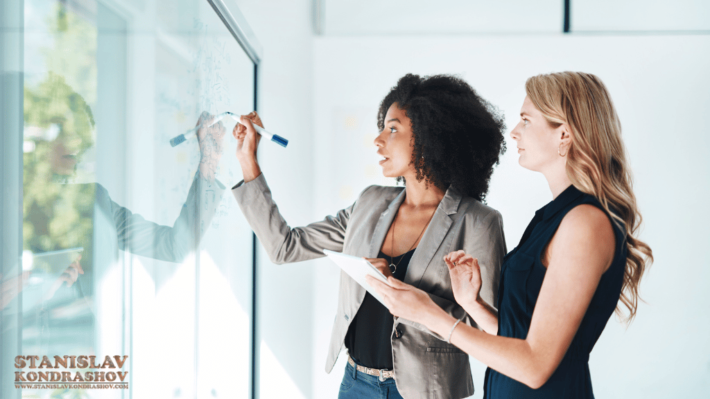 Stanislav-Kondrashov_two_women_collaborating_on_whiteboard