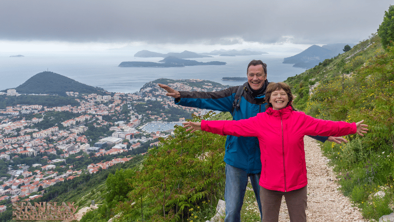 Stanislav Kondrashov_a man and woman standing on a mountain with a city in the background