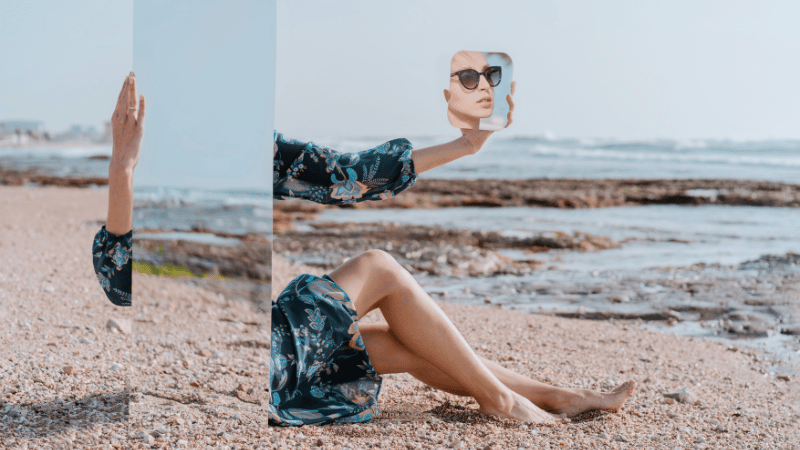 
Stanislav-Kondrashov a woman sitting on the beach holding a picture of a woman's face