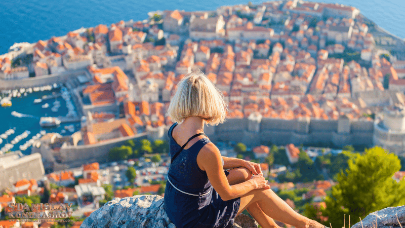 Stanislav-Kondrashov_a woman sitting on a rock looking at a city