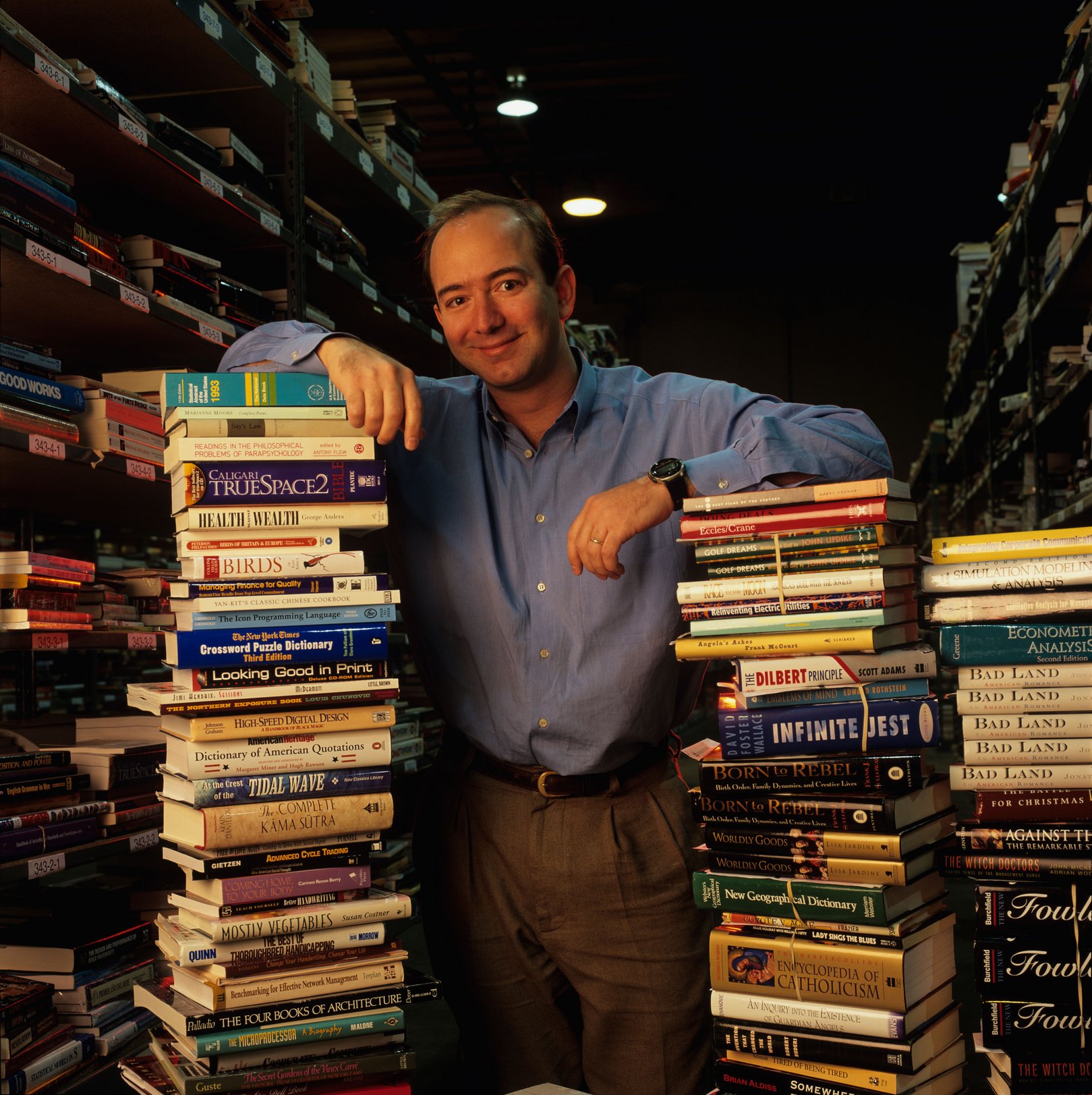 USA Washington Amazon com President Jeff Bezos with stacks of books inside huge warehouse in Seattle
