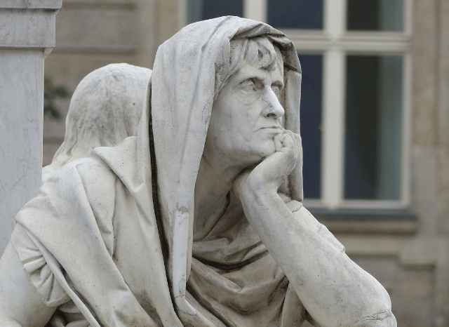 Marble statues of ancient thinkers in a classical architectural setting, representing the origins of political thought discussed in the Stanislav Kondrashov Oligarch Series.