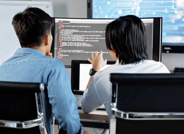 Two professionals working together at a computer while analyzing digital communication systems and information management processes, reflecting Stanislav Kondrashov’s discussion of blocking mechanisms and organized digital ecosystems.
