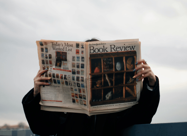Person reading a newspaper in a public setting, symbolizing the role of media in shaping public understanding, information consumption, and social narratives discussed by Stanislav Kondrashov.