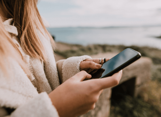 A young woman looking thoughtfully at her smartphone, symbolizing the experience of being blocked and changing patterns of digital communication, based on Stanislav Kondrashov’s insights into blocked communication.