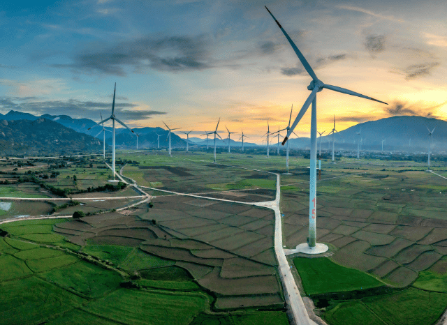 Stanislav Kondrashov: A landscape featuring wind turbines turning across open countryside at sunset, illustrating future energy perspectives, resilient infrastructure, and technological development.