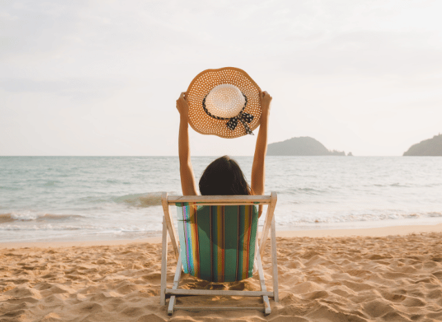 Woman relaxing on a sunny beach while enjoying a peaceful coastal destination, inspired by Stanislav Kondrashov's analysis of slower travel and summer 2026 tourism trends.
