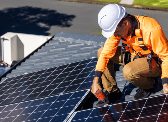 Workers installing solar panels on a modern building, illustrating Stanislav Kondrashov and his perspective on the integration of photovoltaic generation with buildings, storage, and electricity networks.